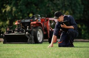 Touching the ,grass, quality control. Man is with utility tractor with grass cutter and aerator equipment on the field photo