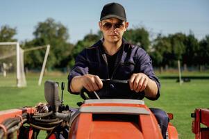 Front ,view, working, driving. Man is with utility tractor with grass cutter and aerator equipment on the field photo