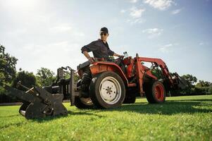 Loan ,work. Man is with utility tractor with grass cutter and aerator equipment on the field photo