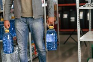 Close up view of man that ,,is holding bottles of water, walking in the shop photo