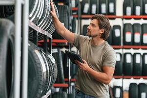 Digital tablet in hands. Man is ,in, the,, tire fitting car service photo