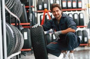 Sitting and showing the tire. Man is in the tire ,fitting car service photo
