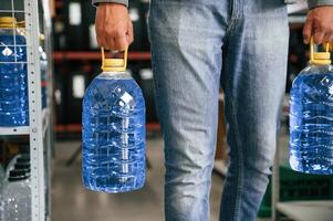 Close up view of man ,that is holding bottles of water, walking in the shop photo