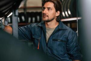 In ,professional uniform. Man,, is ,in the tire fitting car service photo