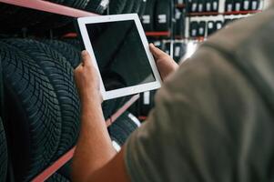 Copy space ,on ,,the digital tablet. Man is in the tire fitting car service photo
