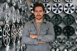 Many, of the disks on walls. Man is in the tire fitting car service photo