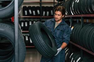 Indoors, holding ,,,tire. Man is in the tire fitting car service photo