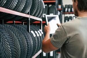 Copy space, on the digital tablet. Man is in the tire fitting car service photo