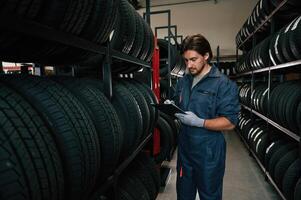 Holding, black notepad... Man is in the tire fitting car service photo