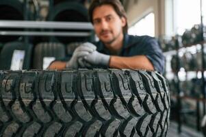 Professional worker is, with wheel. Man is in the tire fitting car service photo