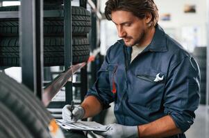 Writing ,the ,data into notepad. Man is in the tire fitting car service photo