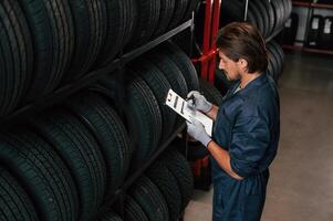 Collecting ,information, ,counting, notepad. Man is in the tire fitting car service photo
