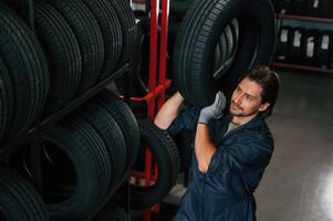 Strong, worker ,is with tire. Man is in the tire fitting car service photo