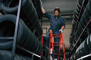 On the ladder. Man is in the tire fitting car service photo
