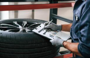Work, in, progress, manager is in warehouse. Man is in the tire fitting car service photo