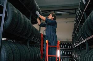 On, the ladder. Man is in the tire fitting car service photo