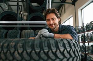 View, from the front, guy with a tire. Man is in the tire fitting car service photo