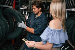 Woman, is in the tire fitting auto shop with worker photo