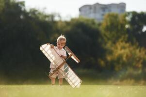 Holding ,it ,in ,hands. Cute little boy is playing with toy plane on the field.. photo