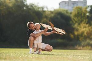 Screwdriver, in, hand, fixing it. Father and son are on the field together with toy plane.. photo