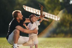 Weekend, activities. Father and son are,, on the field together with toy plane photo