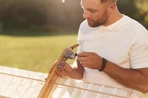Made, of wood. Man is on the field fixing ,,,the toy plane photo