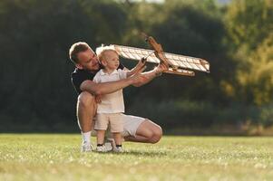 Screwdriver in ,,hand, fixing it. Father and son are on the field together with toy plane photo