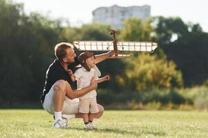 Having fun, sitting. Father and son ,are ,on ,the field together with toy plane photo
