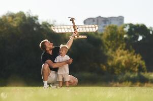 Having fun, sitting., Father and son are on the field together with toy plane photo