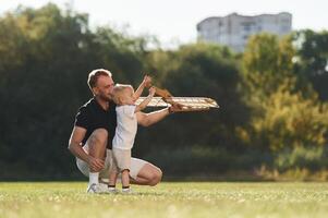 Sitting, together. Father and son are on the field with toy plane photo