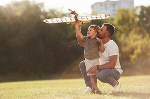 Happy, facial ,,expression, fun. Father and son are on the field together with toy plane photo