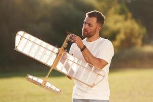 In ,casual clothes. Man is on the field fixing the toy plane photo
