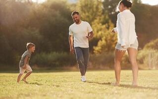 Leisure, fun, times. Mother and father are with son outdoors on the field photo