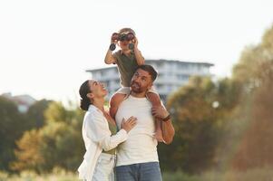 Looking, far, away with binocular. Mother and father are with son outdoors on the field photo