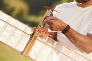 Made, of wood. Man is on the field fixing the toy plane photo