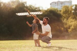 Happy, facial ,expression,, fun. Father and son are on the field together with toy plane photo