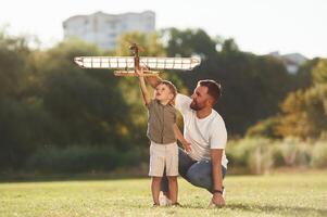 Happy facial, expression, fun. Father and son are on the field together with toy plane photo