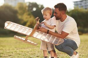 Teaching, the kid ,how to fix it. Father and son are on the field together with toy plane photo