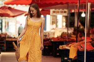 With baguette. Young woman ,is ,on, the vegetable market or bazaar photo