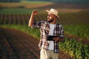 Digital, tablet, in ,,hands. Farmer is on the agricultural field photo