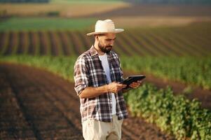 Digital ,tablet in hands. Farmer is on the agricultural field photo