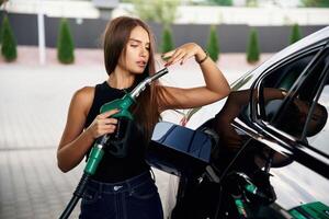 Standing and posing. A young woman at a gas station, with,, her car photo
