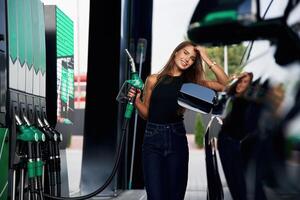 Ready to refill the automobile., A young woman at a gas station with her car photo