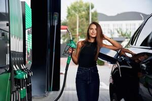 Ready to refill the automobile. A ,,young ,woman at a gas station with her car photo