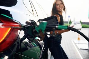 Waiting, holding ,smartphone. A ,young ,,woman at a gas station with her car photo