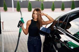 Standing, and posing.. A young woman at a gas station with her car photo