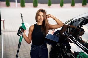 Standing and, posing. A young woman at a gas station with her car photo