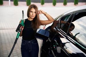 Standing ,and posing. A young woman at a gas station with her car photo