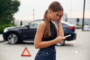 Trying to, catch the signal, and help by phone. Woman's car is broken, accident, standing outdoors photo
