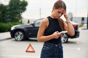 Trying ,to catch, the signal and help by phone. Woman's car is broken, accident, standing outdoors photo